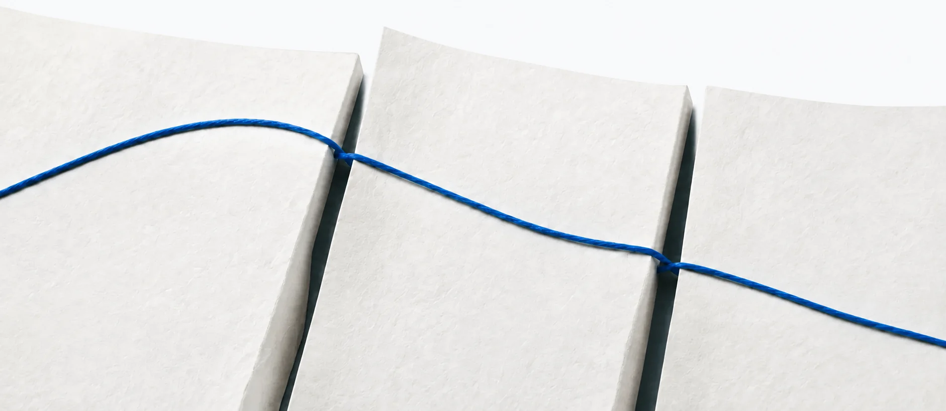 One blue thread connects separate paper surfaces.
